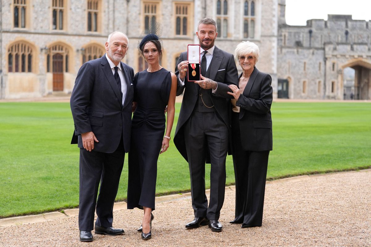 David Beckham poses next to his wife, singer and fashion designer Victoria Beckham and his parents Ted and Sandra with his medal after being appointed as a Knight Bachelor for services to sport and charity at an investiture ceremony at Windsor Castle