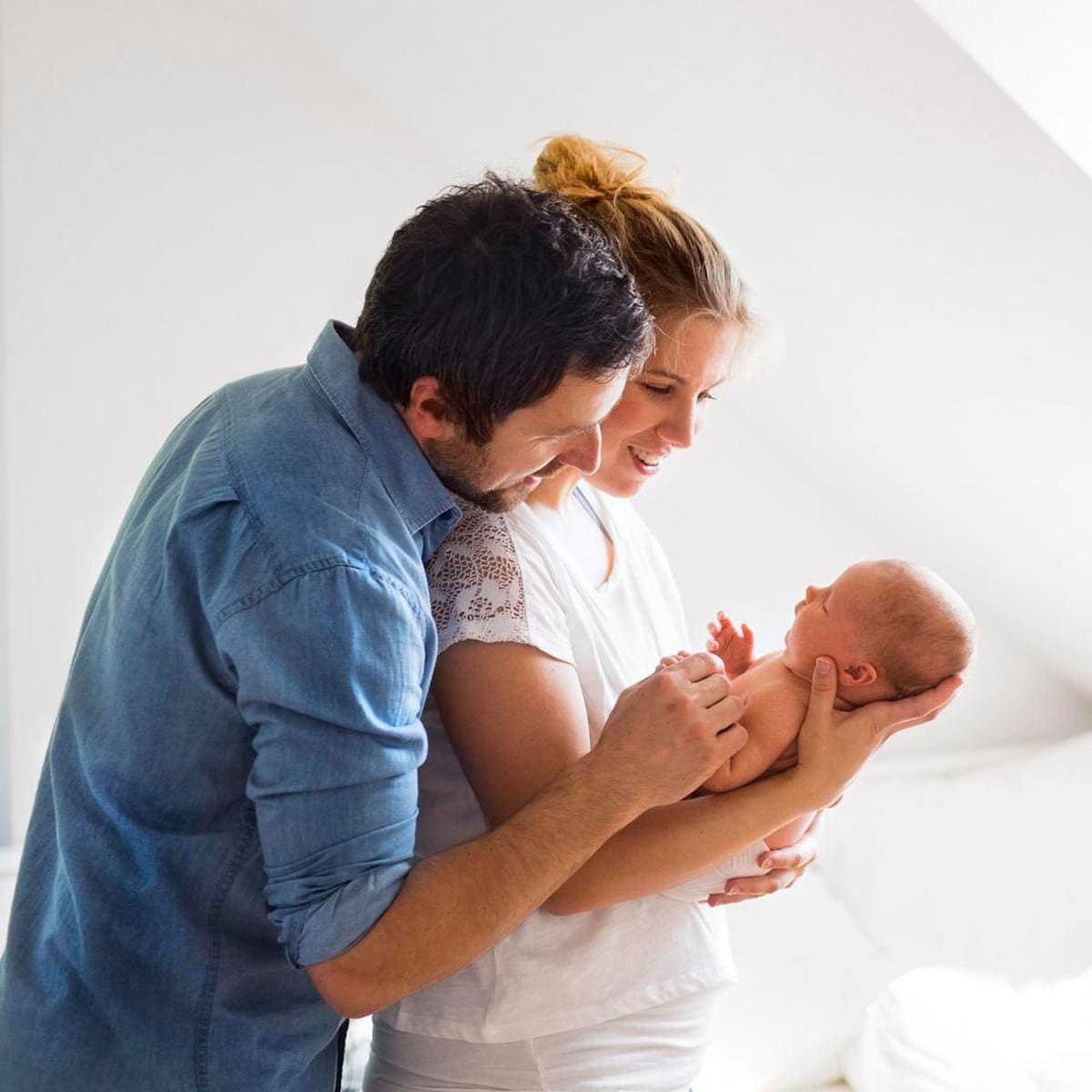 Parents cuddling with little baby at home