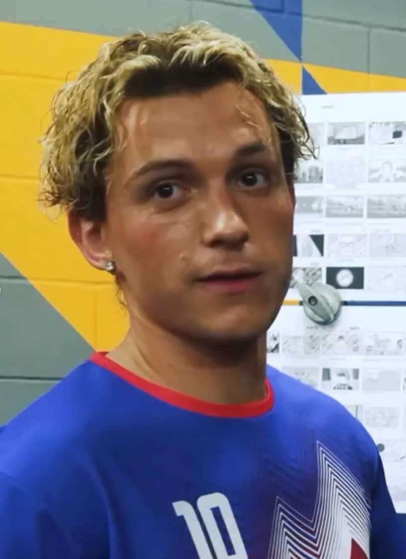Dressed in a red-and-blue soccer jersey, Holland steps into the role of a confident footballer