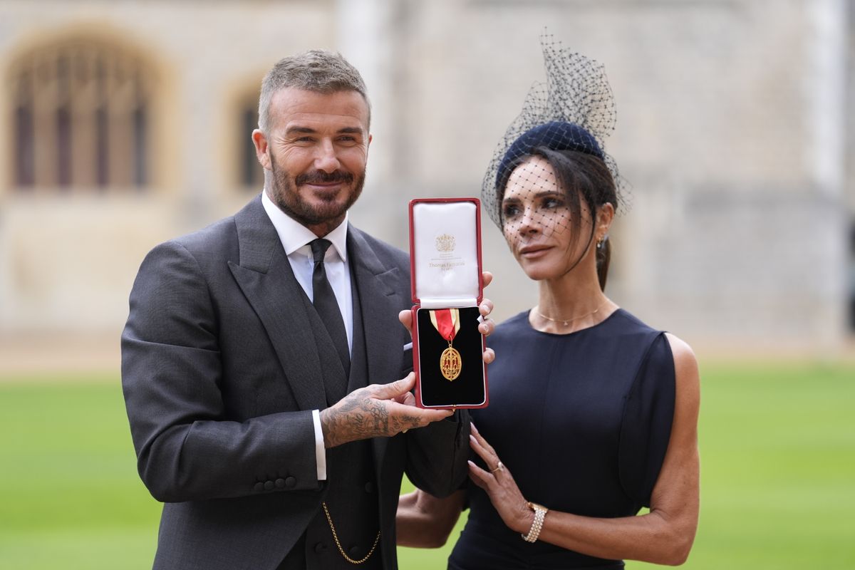 WINDSOR, ENGLAND - NOVEMBER 4: Sir David Beckham poses with his wife Lady Victoria after he was made a Knight Bachelor at an investiture ceremony at Windsor Castle on November 4, 2025 in Windsor, England. 