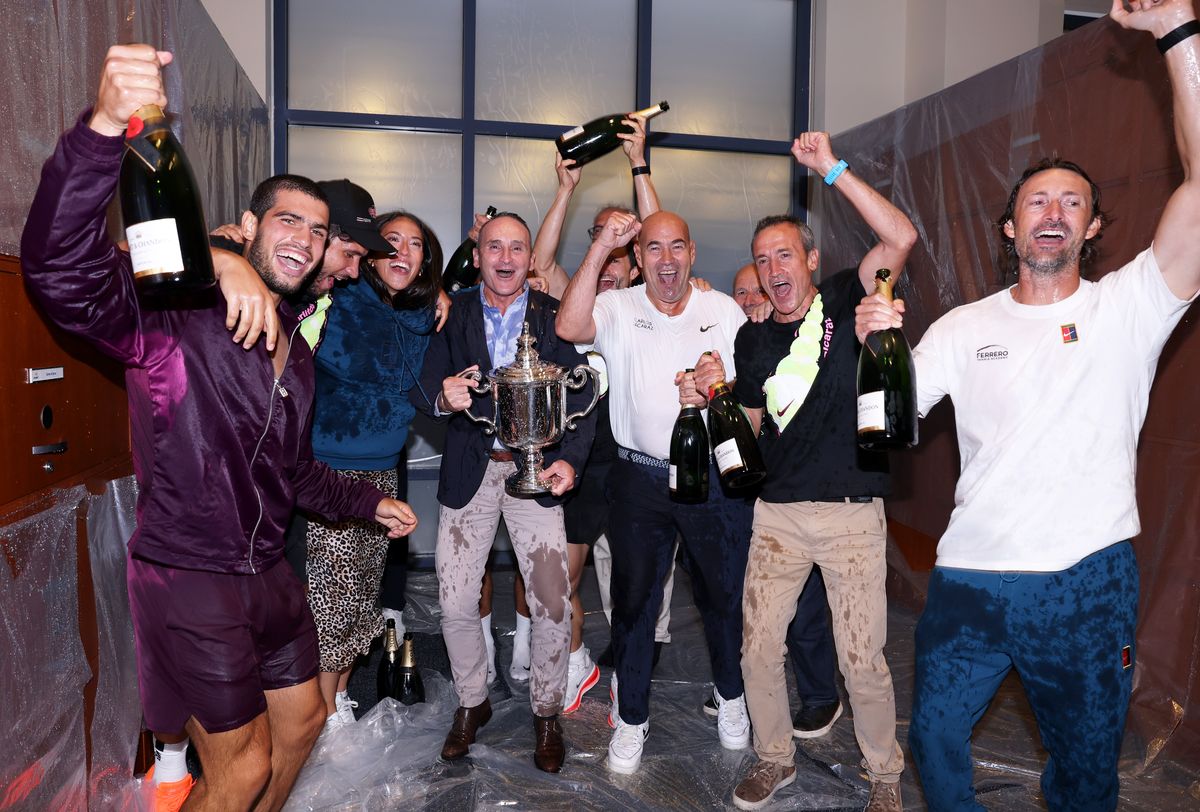 Carlos Alcaraz celebrates with his team and family in the locker room.