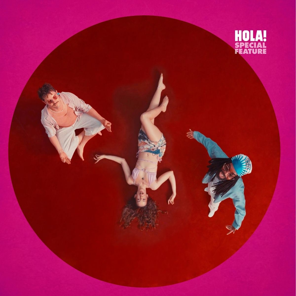 Three individuals in a circle on a red surface. The person on the left wears white, the middle person is in a colorful bikini, and the person on the right wears blue with a patterned hat.