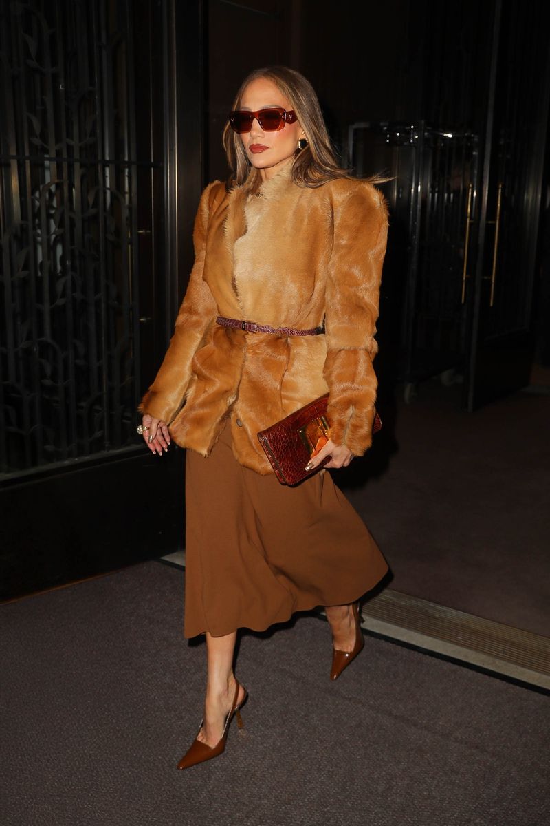 Jennifer López usó gafas de sol PRADA de gran tamaño junto con un abrigo de piel color camel con hombros estructurados y dramáticos.