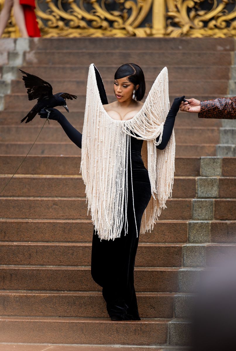 In a sculpted black velvet gown dripping with ivory pearl fringe, Cardi posed with a live raven.