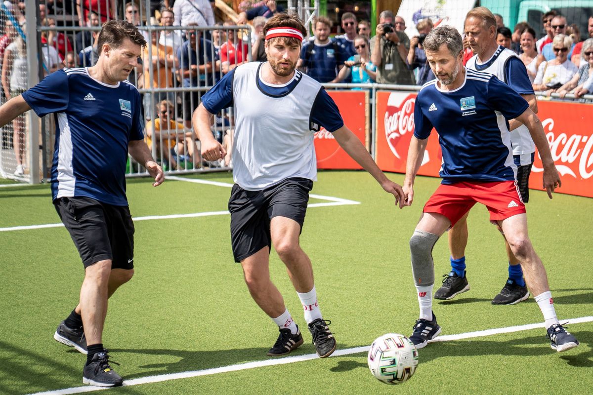 Crown Prince Frederik and former Danish coach and player Michael Laudrup vie for the ball during a show football match during the opening of the UEFA Euro 2020 fan zone 'Football Village' at Ofelia Plads in Copenhagen on June 11, 2021