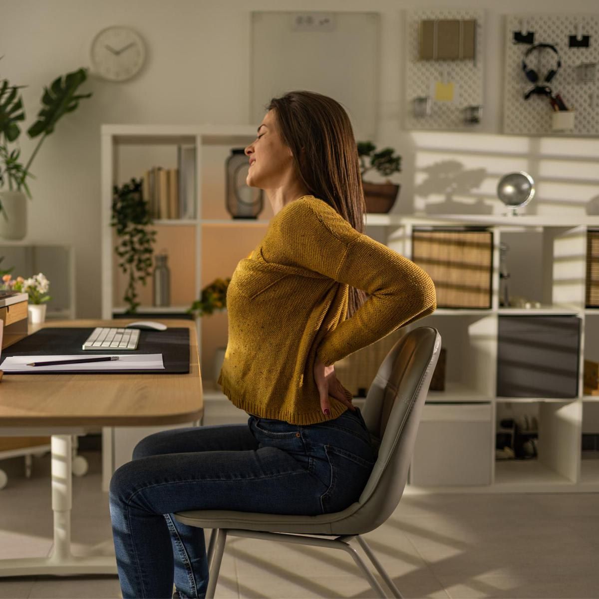 Young businesswoman having backache after working whole day in her home office alone.