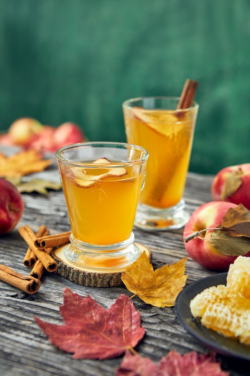 rustic fresh apple cider with apples and leaves on wood