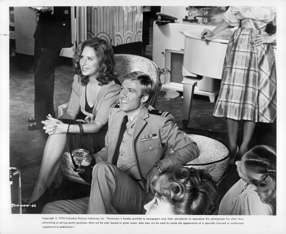 Barbara Streisand and Robert Redford sit smiling looking forward in a scene from the film 'The Way We Were', 1973. 