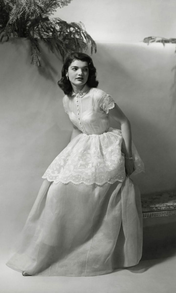 Jacqueline posed for a portrait at age 18 wearing a short-sleeve white dress that featured a lace embroidered overlay.