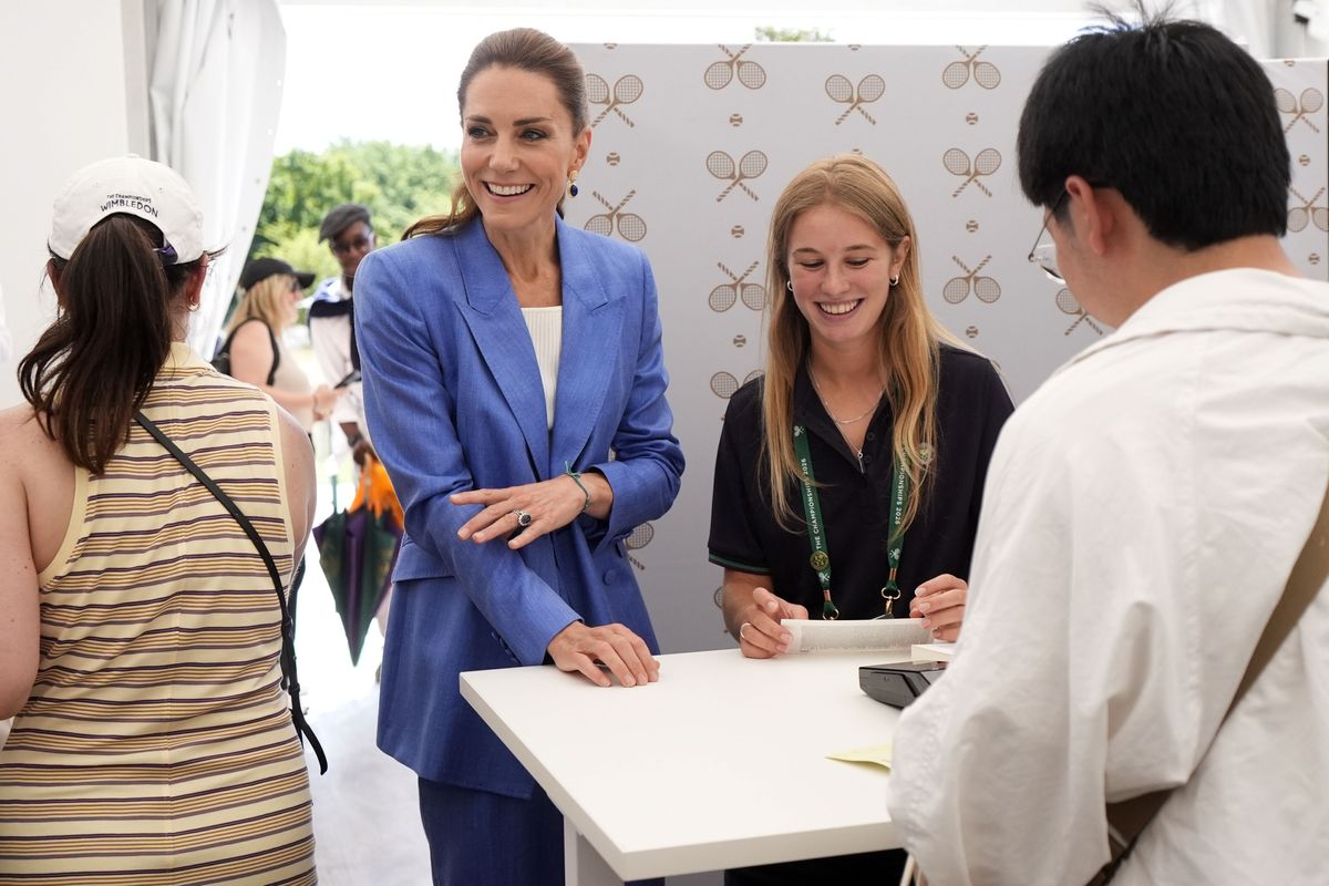 Princess Kate smiles as she chats with visitors while helping distribute tickets ahead of the day's matches.