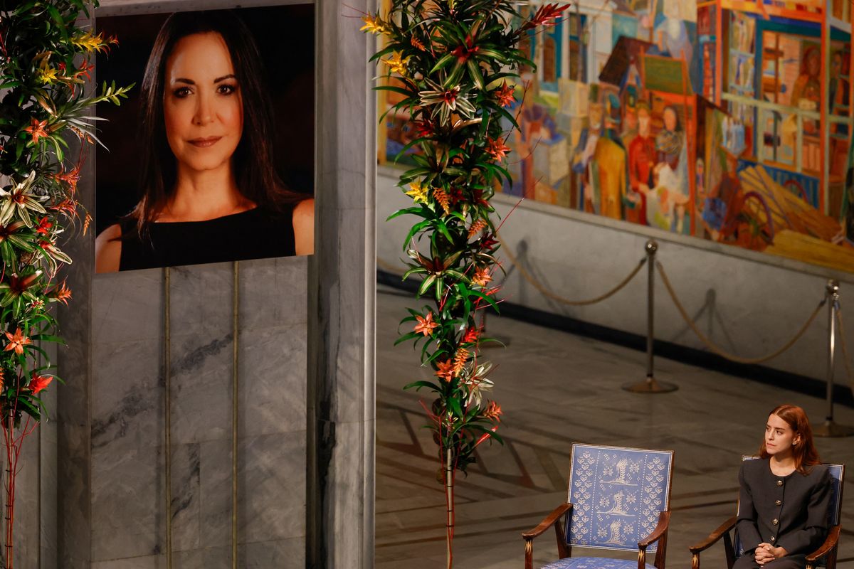 Ana Corina Sosa (R), daughter of Venezuelan opposition leader Maria Corina Machado, sits in her seat with a portrait of her on display at the Nobel Peace Prize ceremony.
