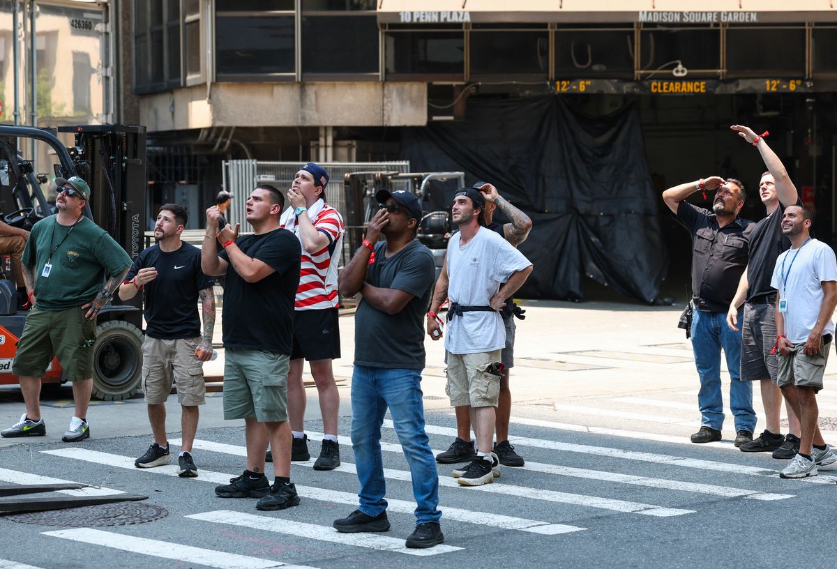 Workers near Madison Square Garden stop and look up toward the Empire State Building in New York on July 1, 2026. Two people climbed to the top of the Empire State Building on July 1 and unfurled a banner.