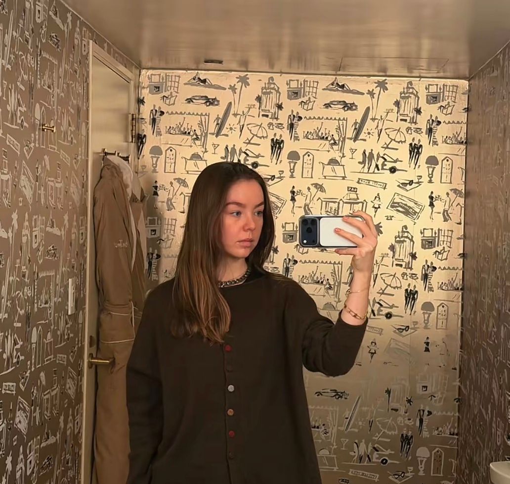 Alexandra’s mirror selfie offers a glimpse of her understated style, with loose hair and a dark cardigan featuring colorful buttons.