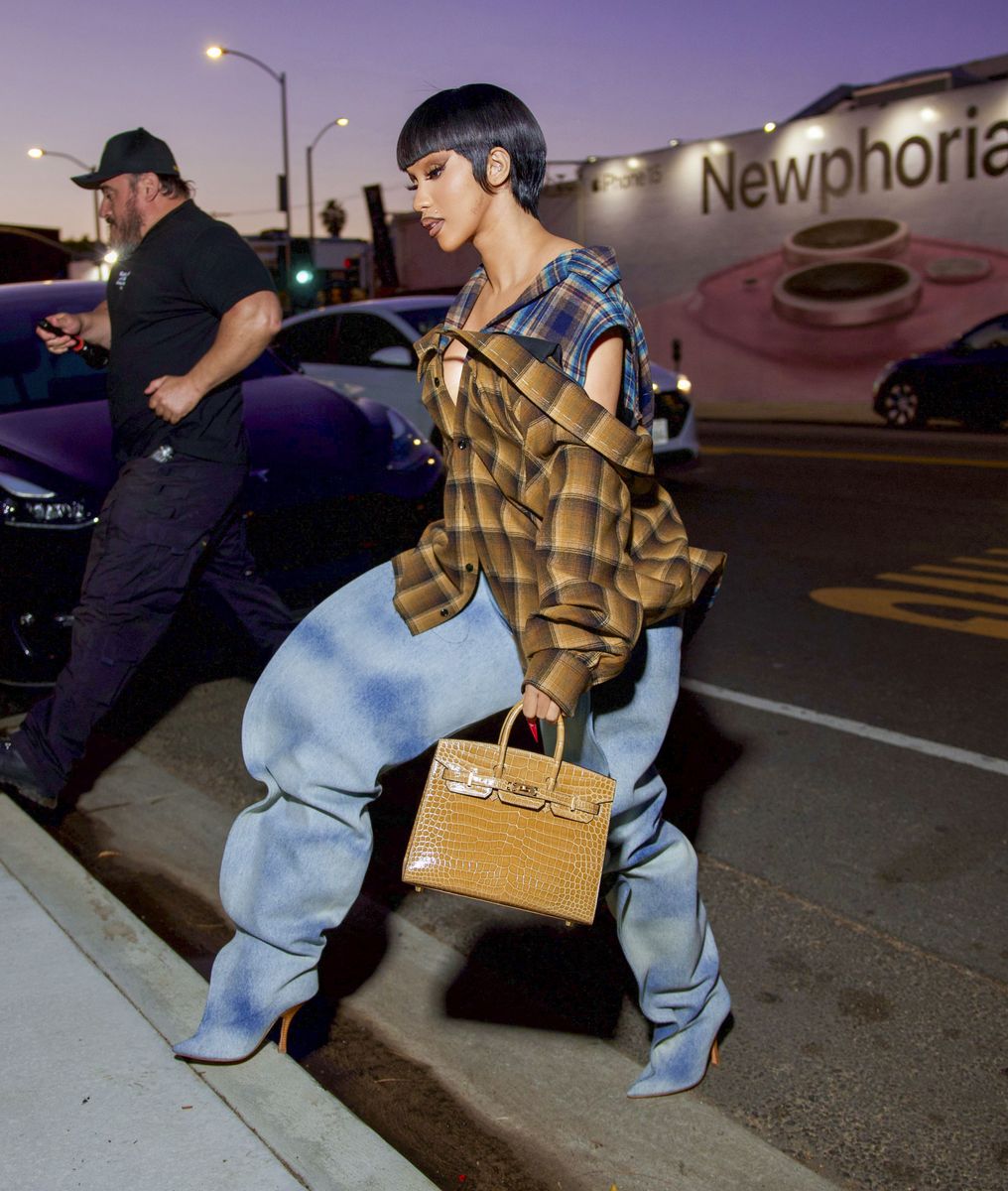 Cardi B paired an oversized plaid shirt and slouchy denim boots with a structured tan Birkin.