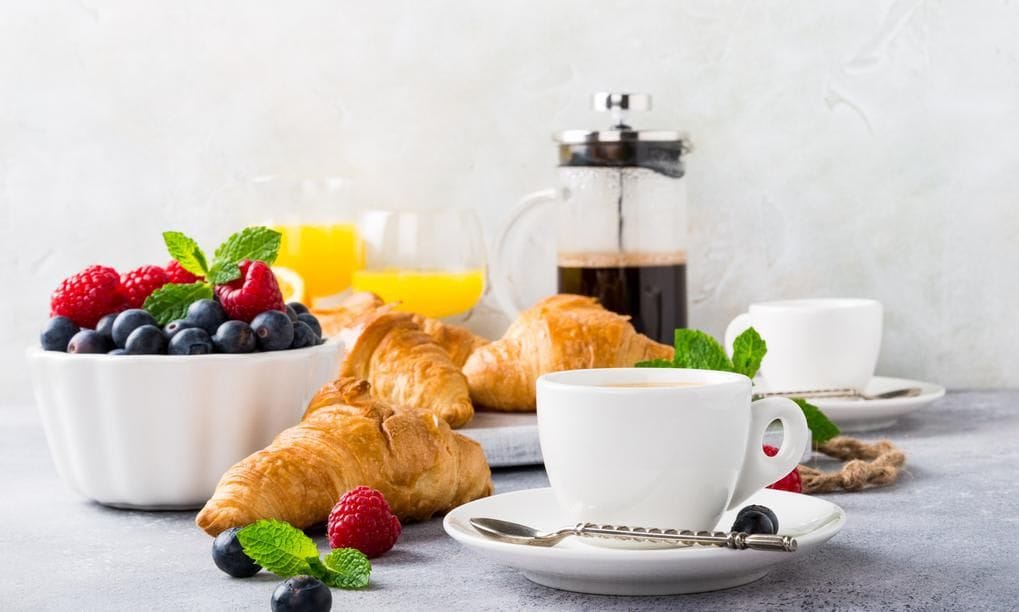 Breakfast with coffee, fruit, and croissants
