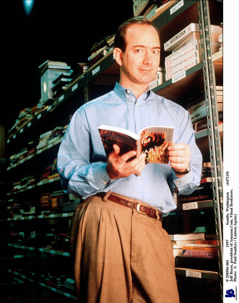 Jeff Bezos, founder & CEO of Amazon.com, poses with a book in an Amazon warehouse, Seattle, Washington, January 1st 1997