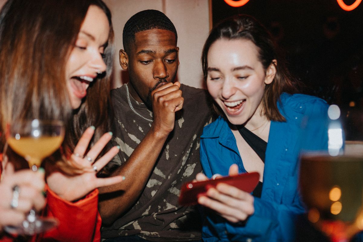 Friends drinking and watching videos on their phones