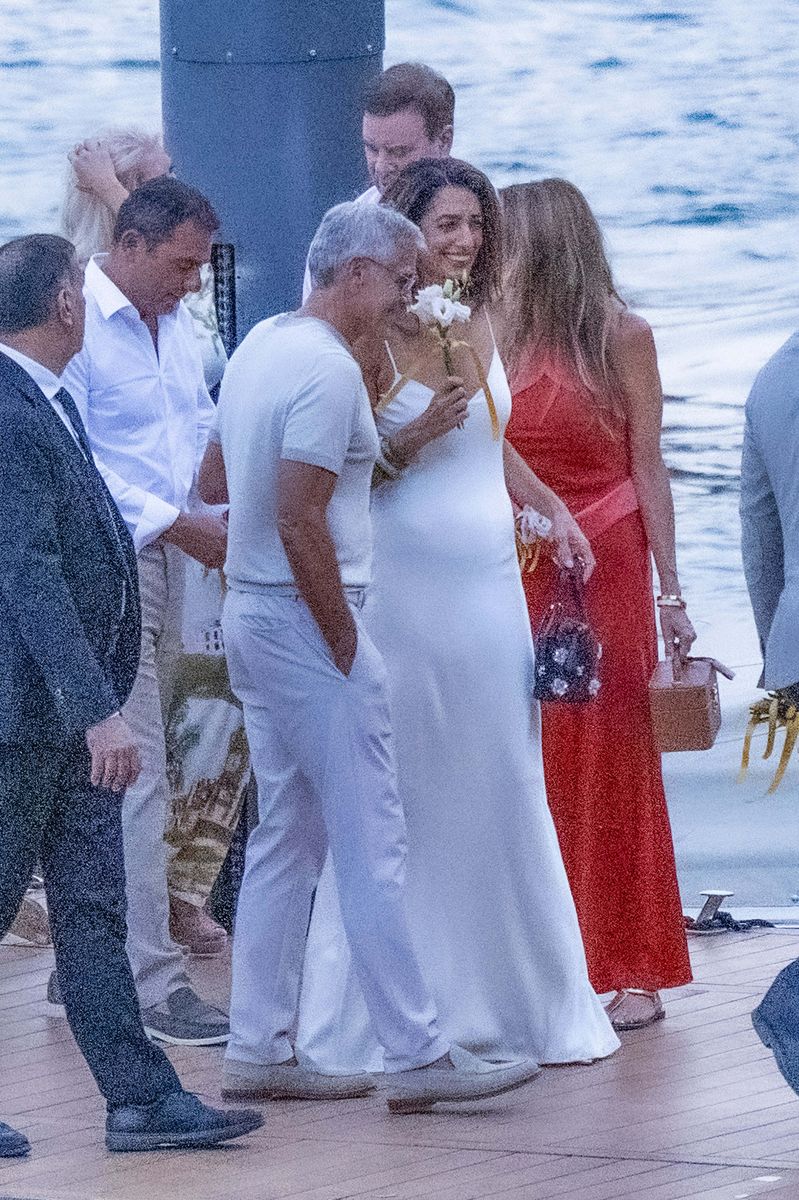 Amal playfully held the flowers near her face after stepping onto the dock at Villa Passalacqua.