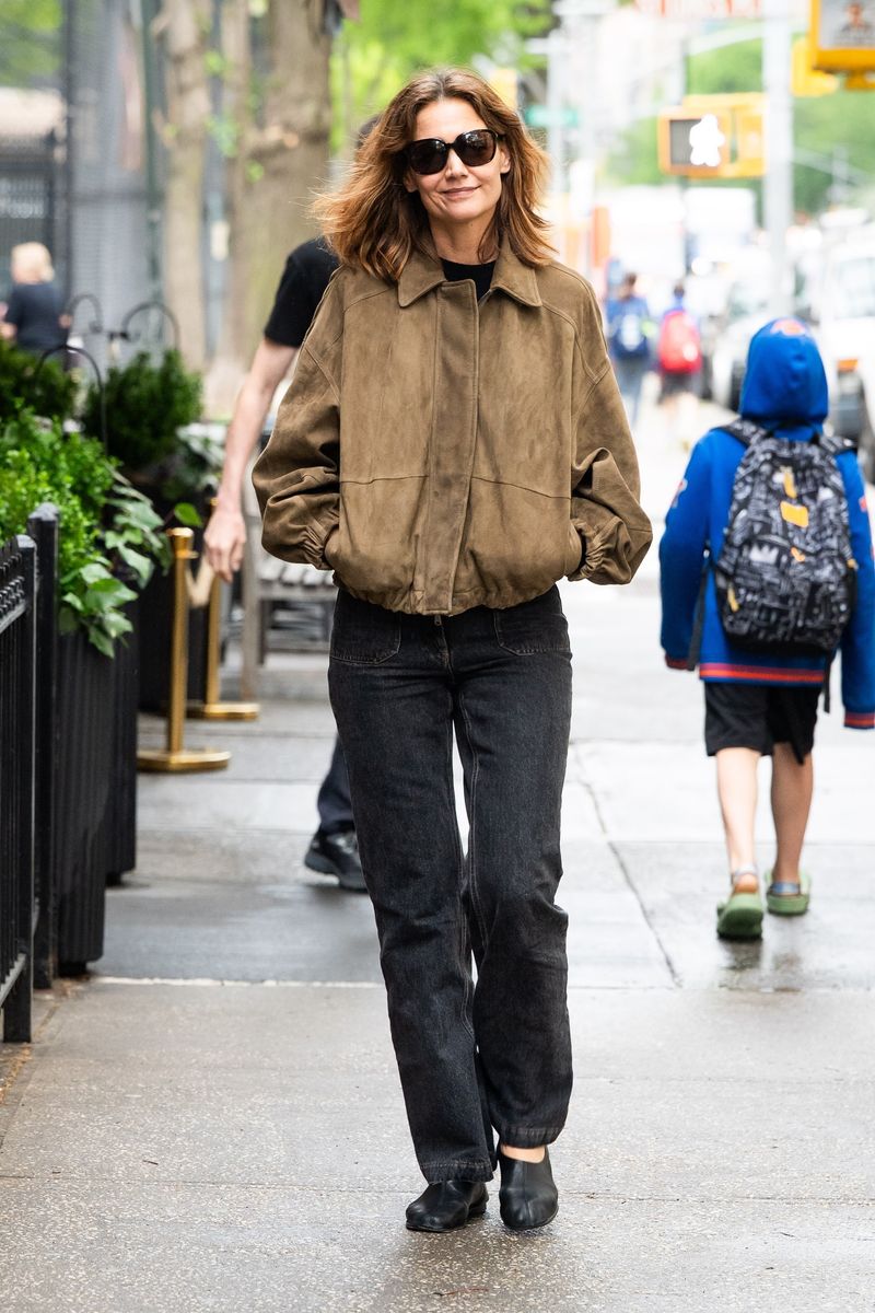 In one recent outing, Holmes embraced earthy neutrals with a suede-like brown bomber jacket styled over dark straight-leg jeans and black shoes.