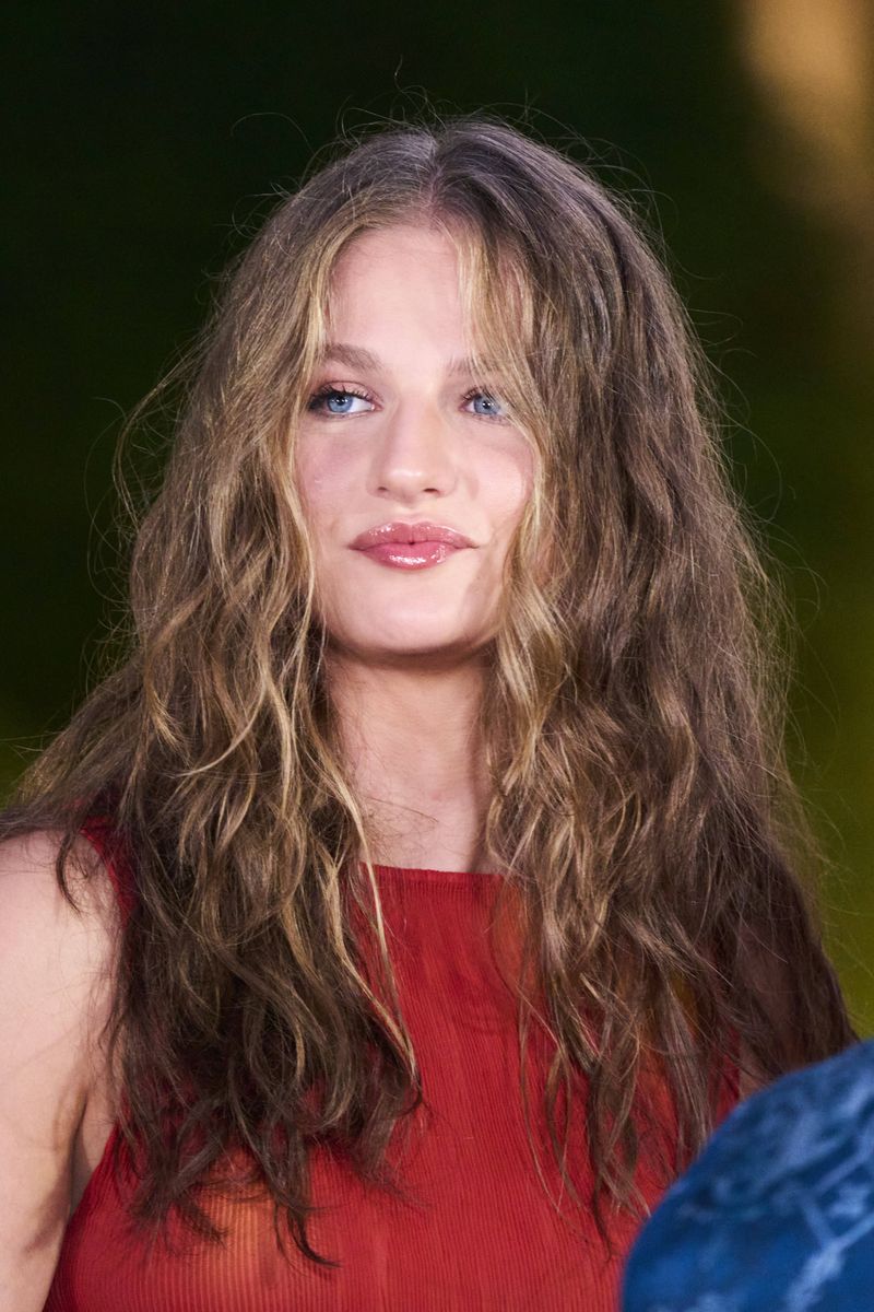 Princess Leonor embraced a more relaxed beauty look, wearing her long hair in voluminous textured waves with face-framing highlights and glossy pink lips.