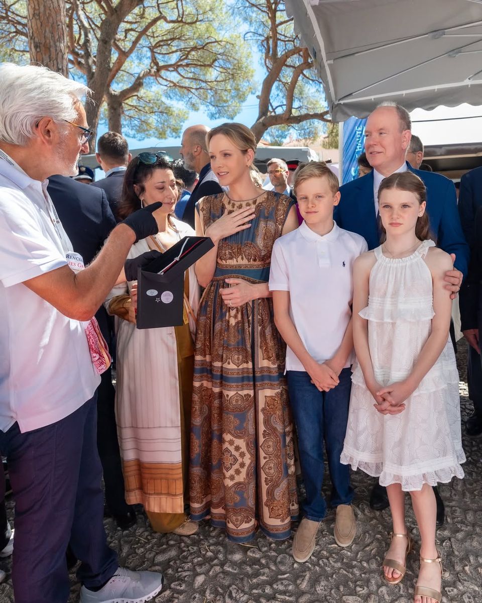 Princess Charlene embraced boho-chic style in a sleeveless paisley-print maxi dress paired with delicate gold jewelry and a soft updo.