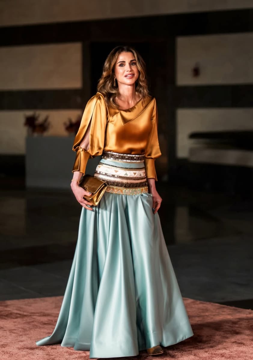 Queen Rania wore a copper-toned top with an asymmetric camisole neckline, puffed sleeves with slit details and fitted cuffs, paired with a spectacular floor-length skirt in aquamarine.