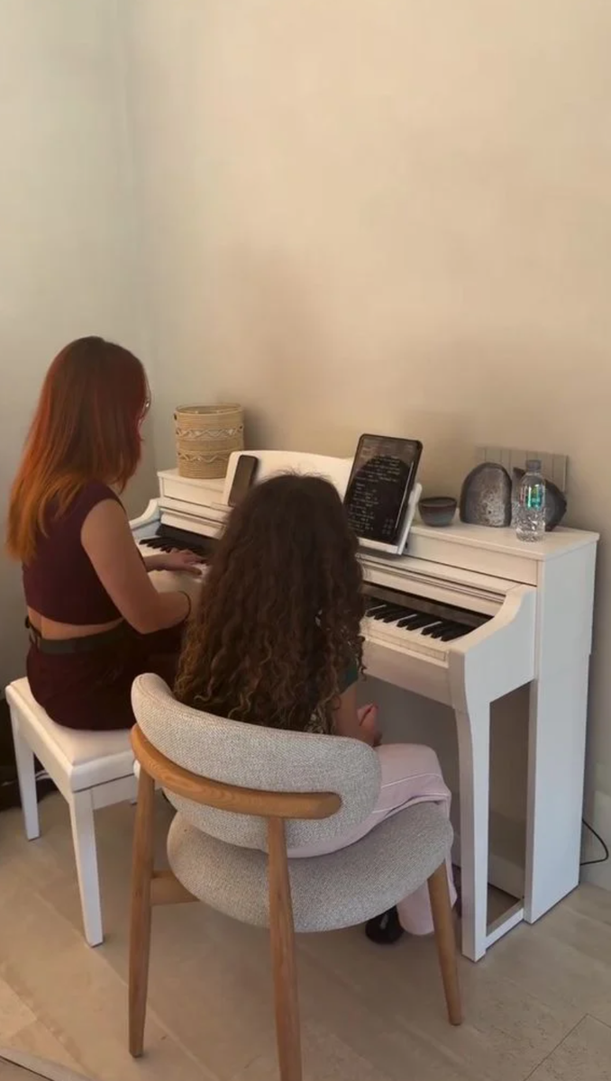 Wearing her signature loose, curly hair, the little girl sat in front of the piano next to her teacher