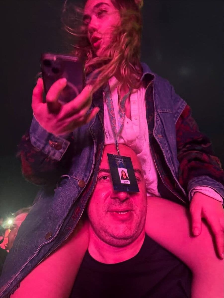 Valentina Paloma on the shoulders of someone who appears to be a security guard, enjoying the festival.