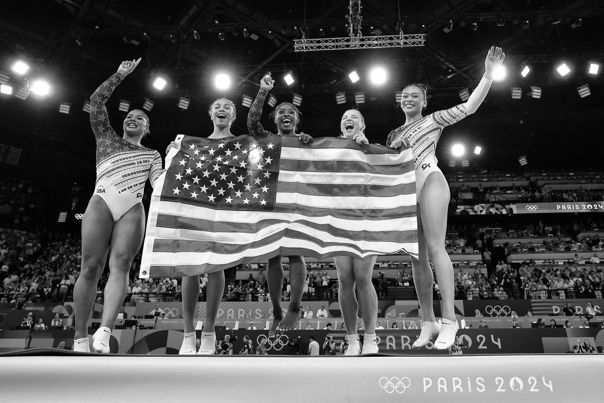 PARIS, FRANCE - JULY 31: (EDITORS NOTE - This image has been converted to black and white) Jordan Chiles, Hezly Rivera, Jade Carey, Sunisa Lee and Simone Biles of Team United States celebrate after winning the gold medal during the Artistic Gymnastics Women's Team Final on day four of the Olympic Games Paris 2024 at Bercy Arena on July 30, 2024 in Paris, France. (Photo by Naomi Baker/Getty Images)
