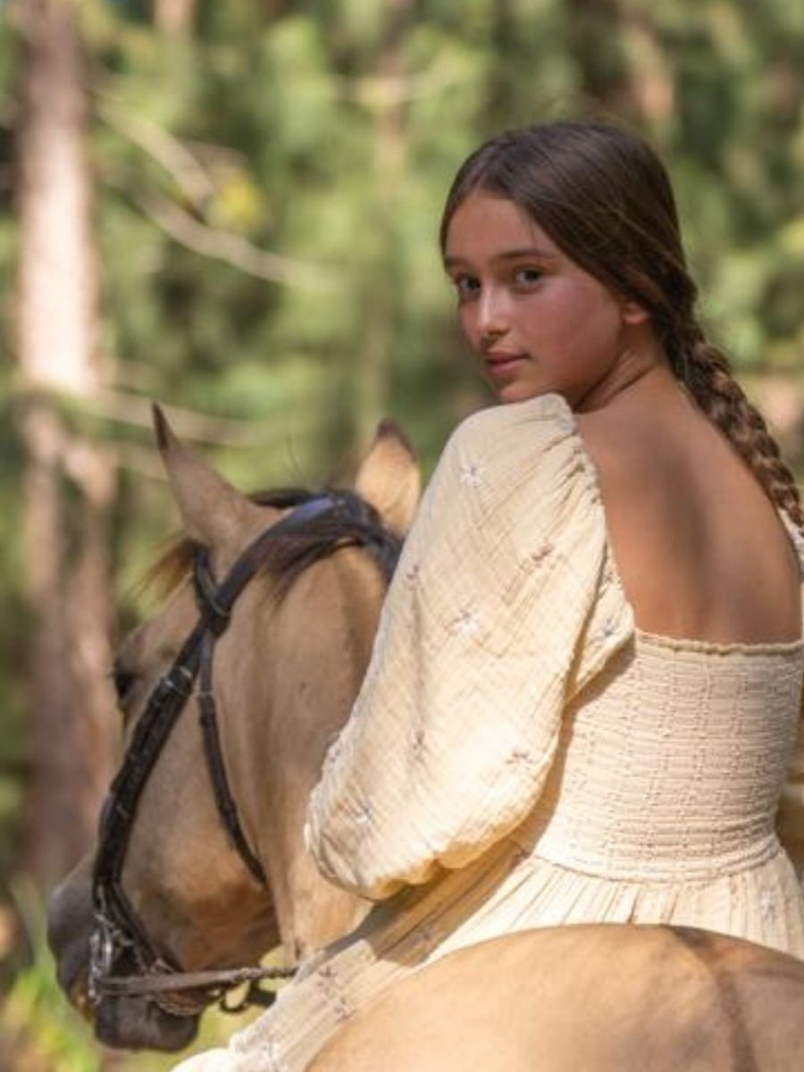 Showing off her passion for horseback riding, 15-year-old Arabella poses in full riding gear alongside her horse.