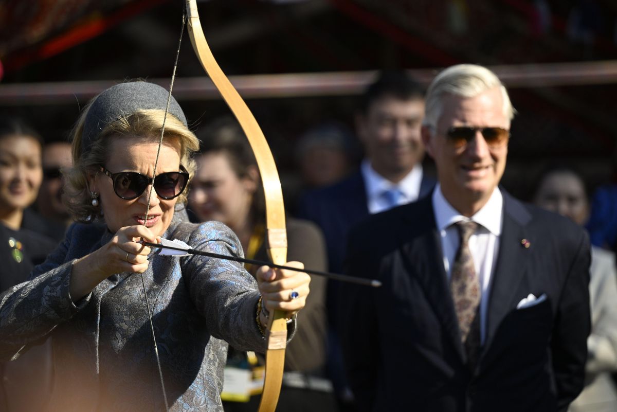 Queen Mathilde drew back her bow as King Philippe watched with a smile during their cultural outing in Kazakhstan.