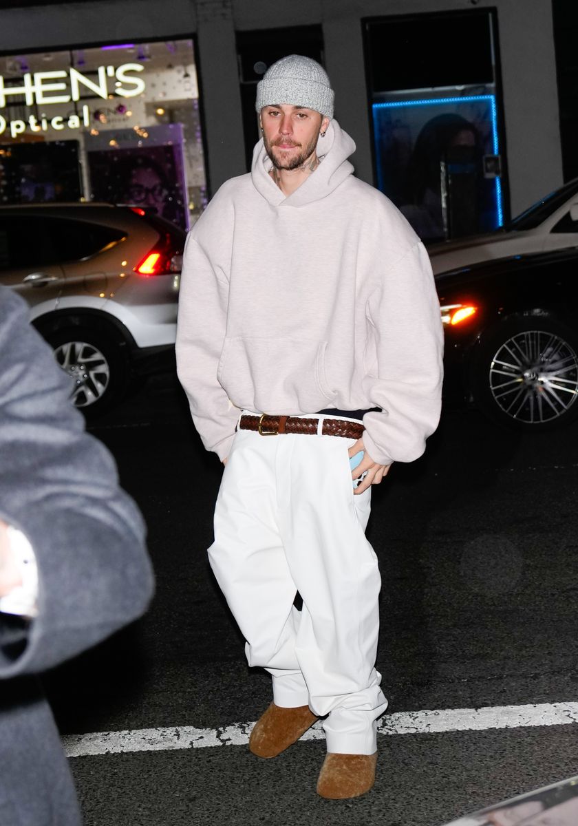 Justin Bieber is seen wearing a hoodie and oversized pants combined with brown boots and a wool hat.