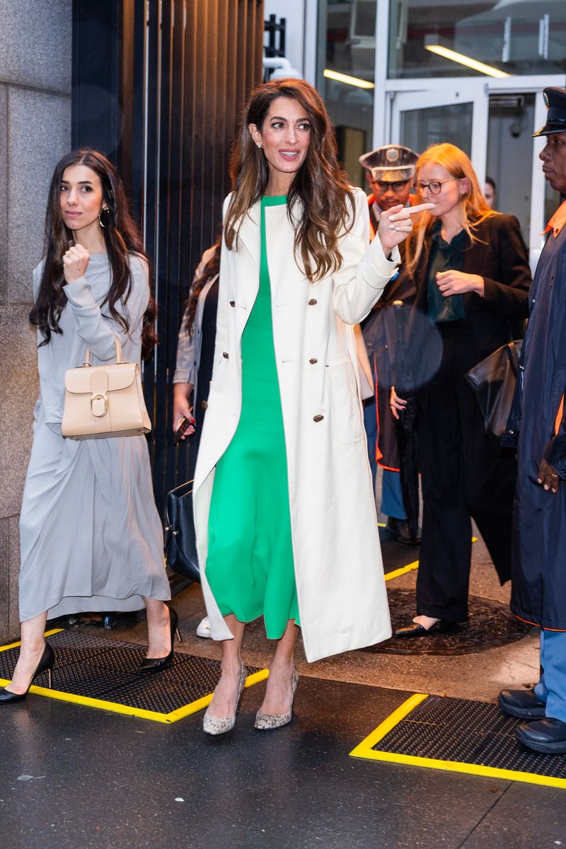Amal Clooney offered a masterclass in transitional fall dressing while visiting the United Nations in New York City in September 2023. She paired a vibrant green sleeveless midi dress with a classic cream trench coat, snakeskin pumps and an oversized black leather tote.