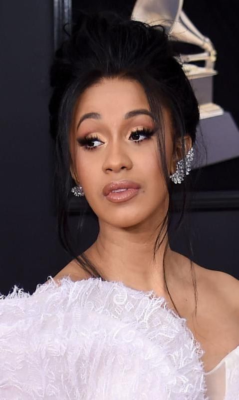 Cardi B con cabello recogido pestañas llamativas y vestido blanco