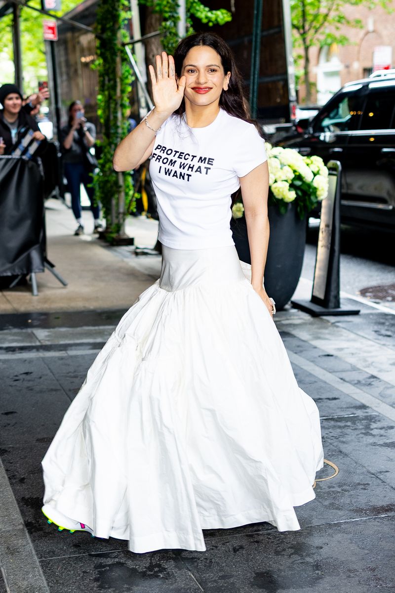 Rosalía checked into her New York hotel before the Met Gala with her spunky signature style. The Spanish singer caught eyes in a white tee with the words “Protect me from what I want,” - a song title from the band Placebo