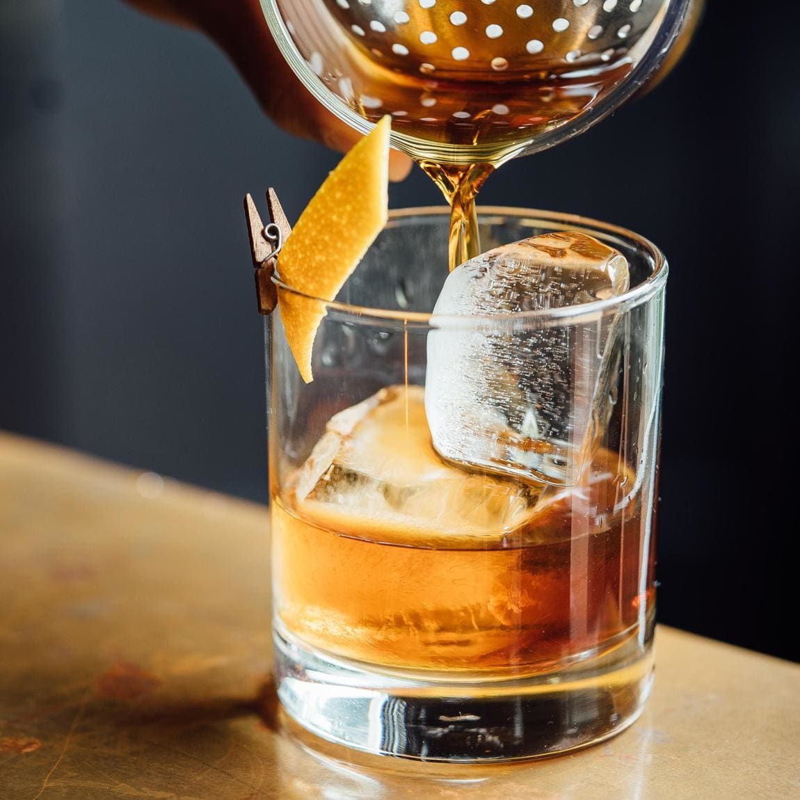 Old Fashioned cocktail being poured into a clear glass
