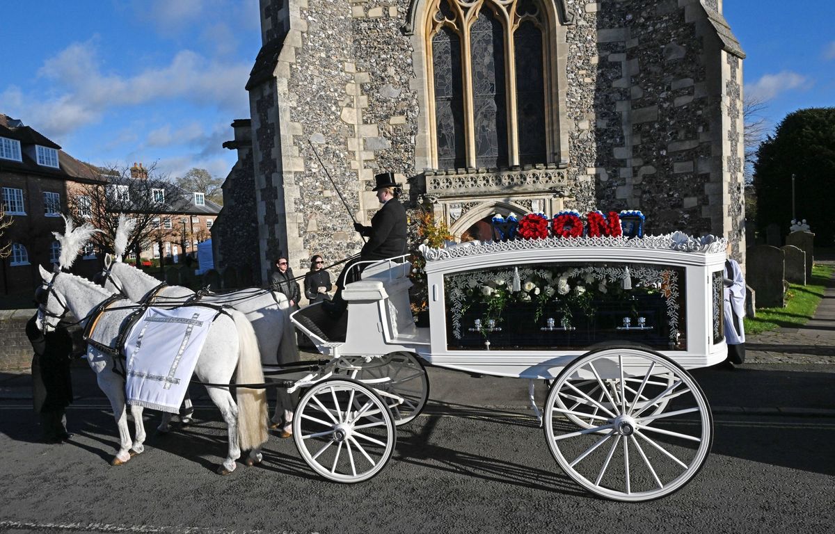 The moment a horse-drawn carriage arrived at the church, carrying a dark blue coffin with silver handles, topped with white roses, for Liam Payne's funeral. 