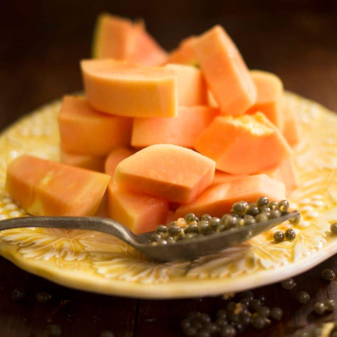 Sliced papaya fruit and papaya seeds on a spoon