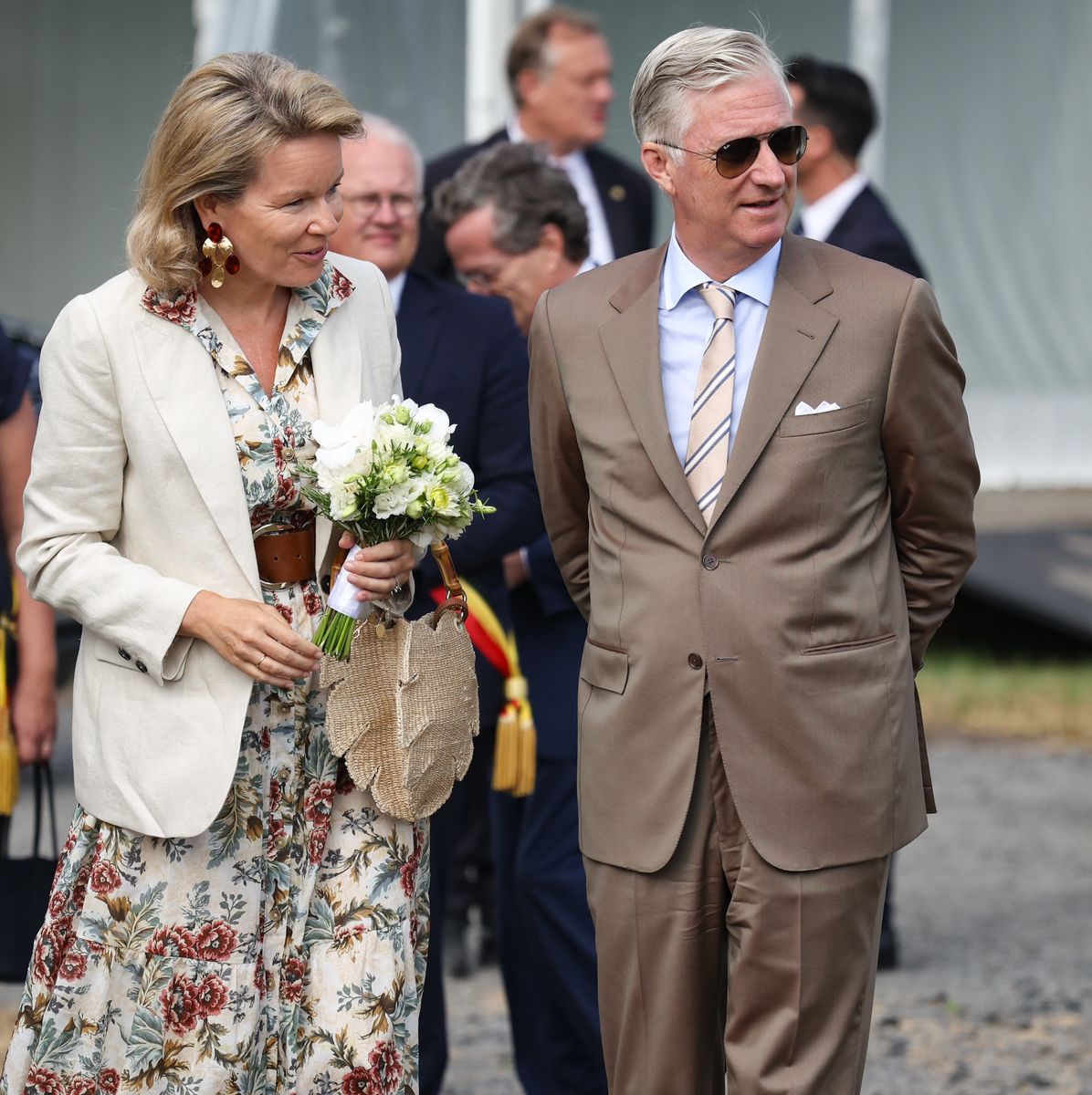 The Belgian queen completed her countryside chic ensemble with a raffia handbag, statement earrings and oversized sunglasses.