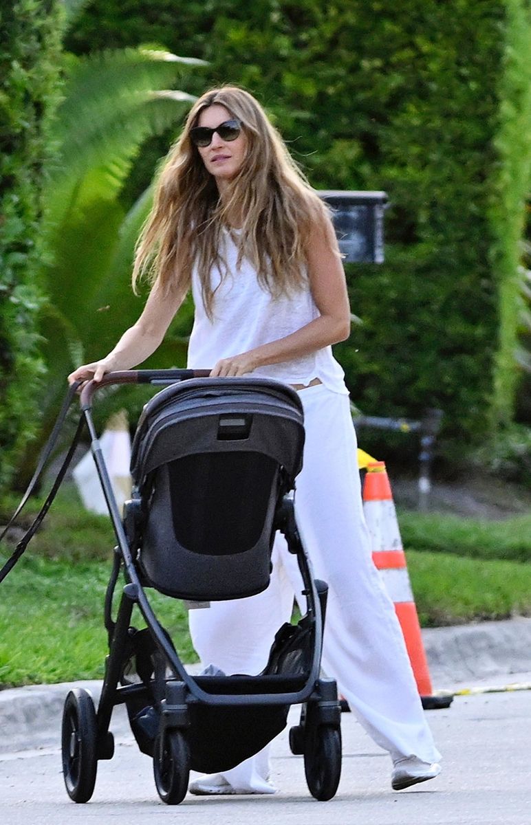 Dressed in a breezy white sleeveless top and matching pants, Gisele looked radiant as she pushed a stroller and played with her dog during the outing. 