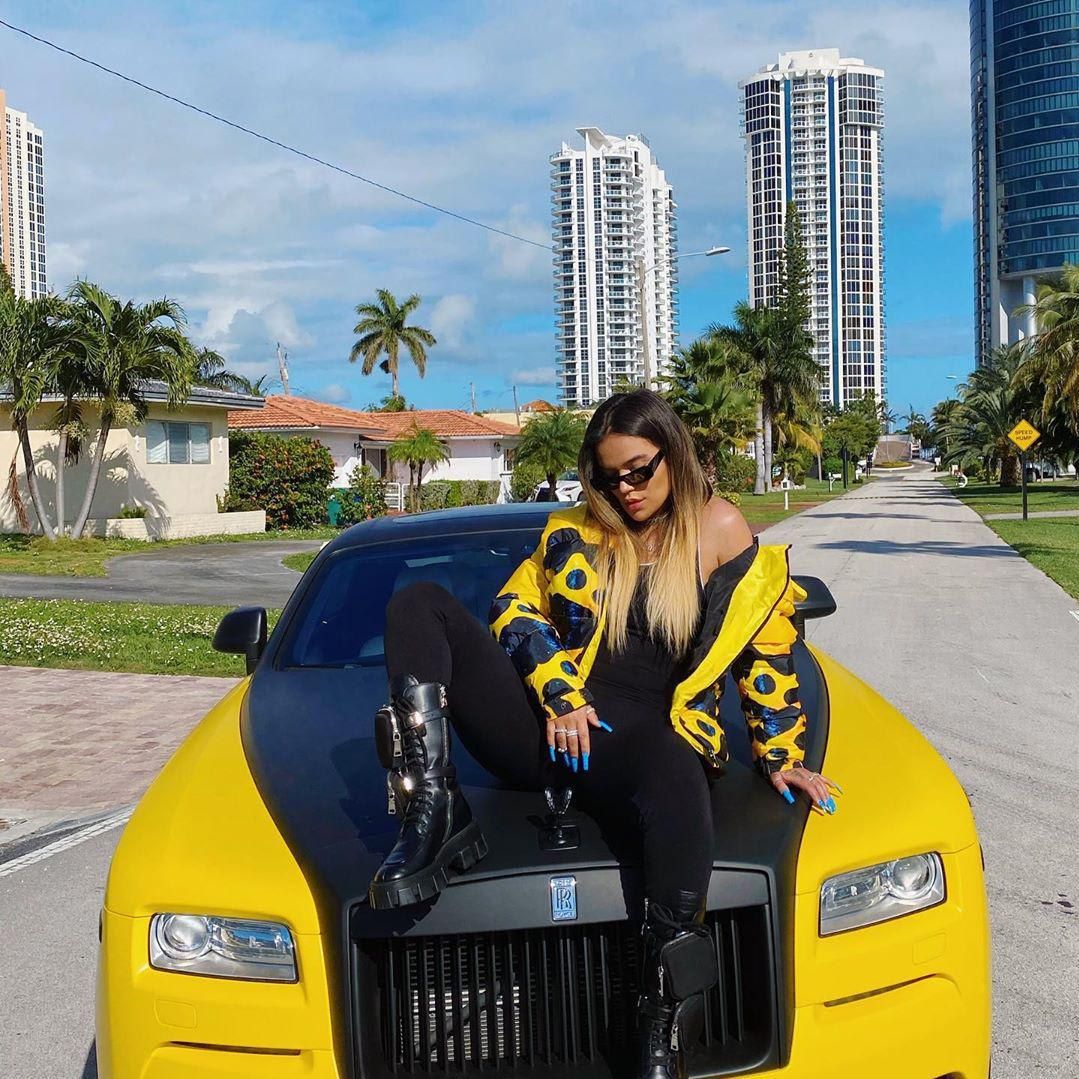 Karol G posing on top of her Rolls Royce, gifted by boyfriend Anuel AA