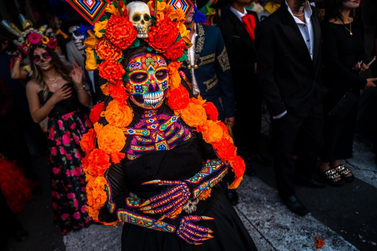 A Mexican woman, dressed as La Catrina and wearing Huichol beaded mask and dress, takes part in the Day of the Dead festivities on November 1, 2022 in Morelia, MichoacÃ¡n, Mexico. Day of the Dead (DÃ­a de Muertos) is a religious holiday which combines the Death veneration rituals of Pre-Hispanic cultures with the Catholic practice. Based on the belief that the souls of the departed return to this world on that day, it is widely celebrated throughout Mexico. People gather while praying or joyfully eating, drinking, or parading in costumes through towns, to remember friends or family members who have died. (Photo by Jan Sochor/Getty Images)