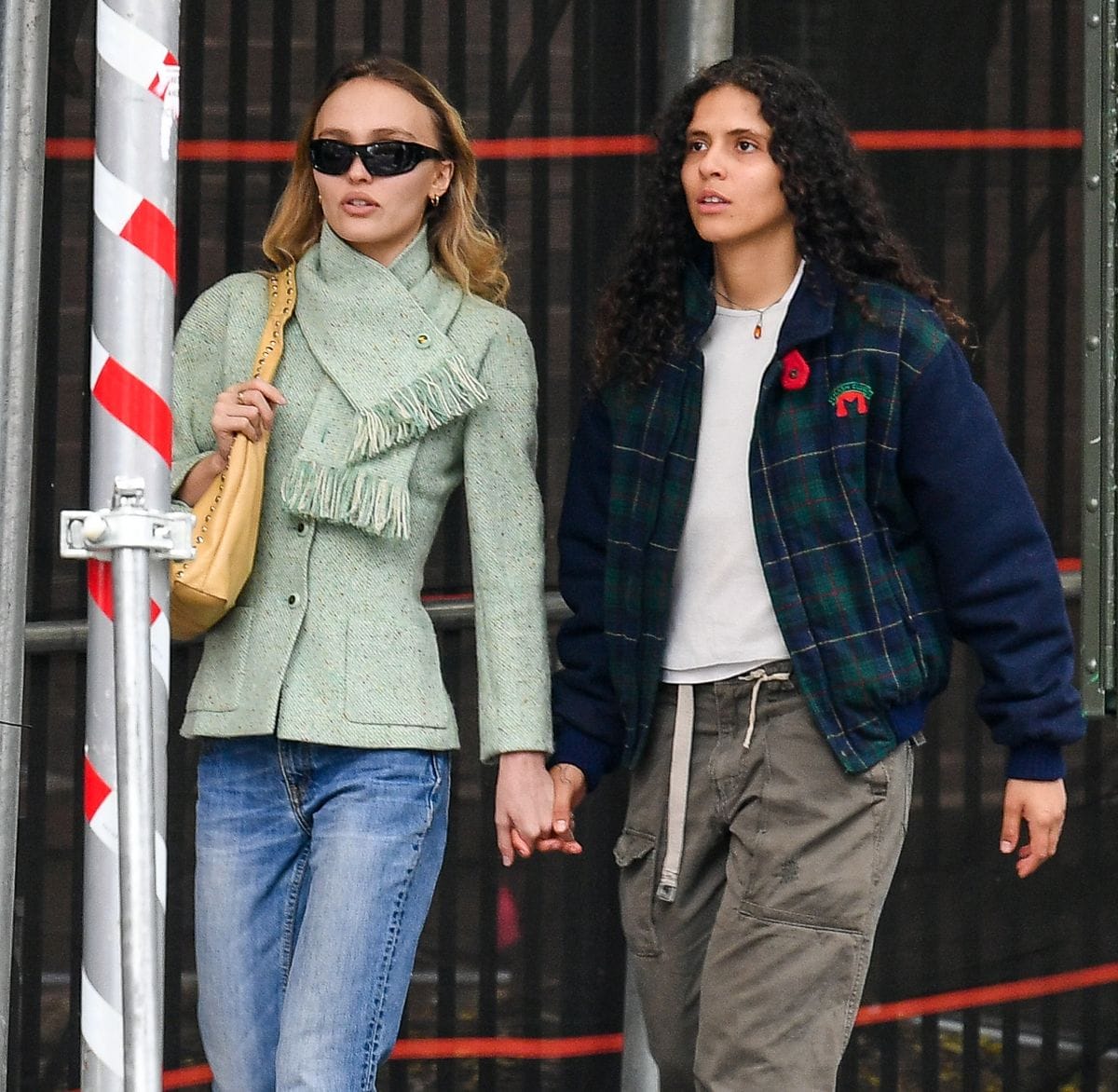 Lily-Rose Depp and girlfriend 070 Shake hold hands while stepping out in New York City. Lily-Rose wore a green jacket, jeans, and ballet flats. Lily's rapper partner wore a plaid jacket, cargo pants, and combat boots. 