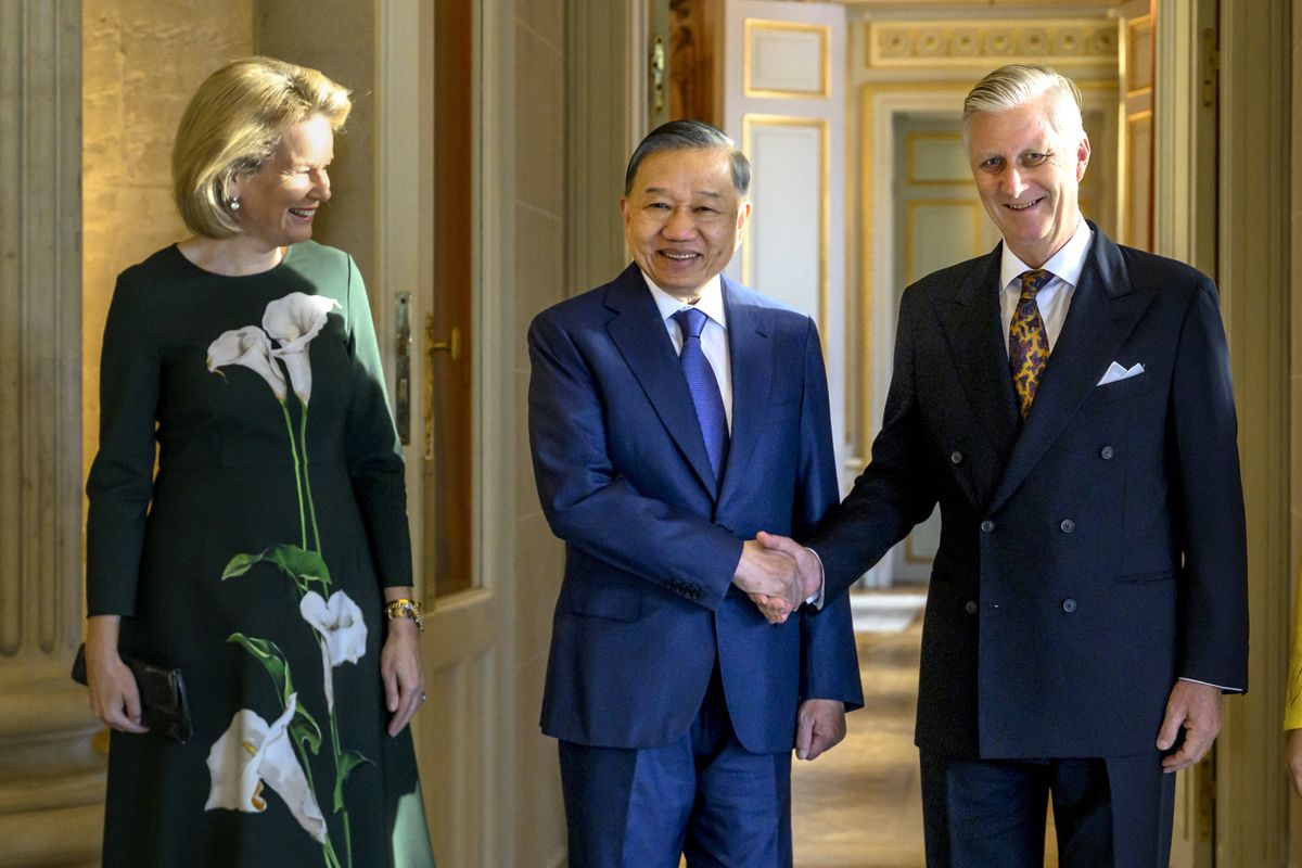 Queen Mathilde's sophisticated ensemble featured a fitted silhouette and dramatic white calla lilies that stood out against the deep green fabric.