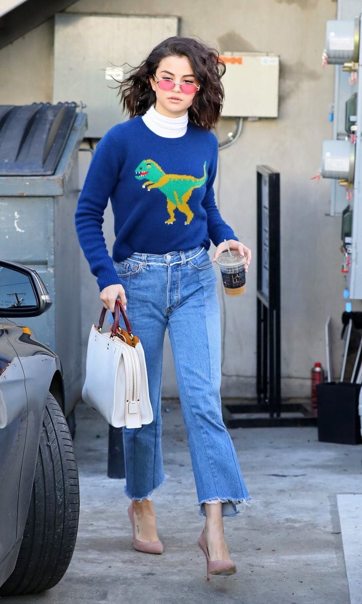 Selena Gomez wearing jeans and a dinosaur sweater