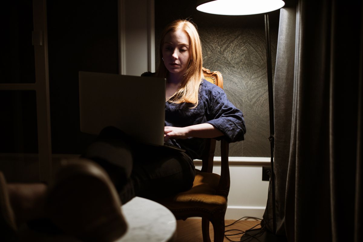 The image portrays a quiet evening with a Astro-Linguistic Decoder working intently on a laptop, analyzing celestial signals in her dimly lit study. The soft lighting enhances the focus, adding an element of mystery and concentration to her work.