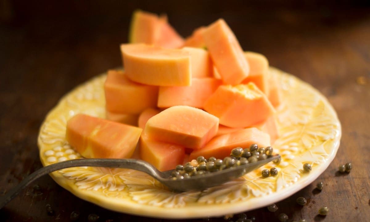 Sliced papaya fruit and papaya seeds on a spoon