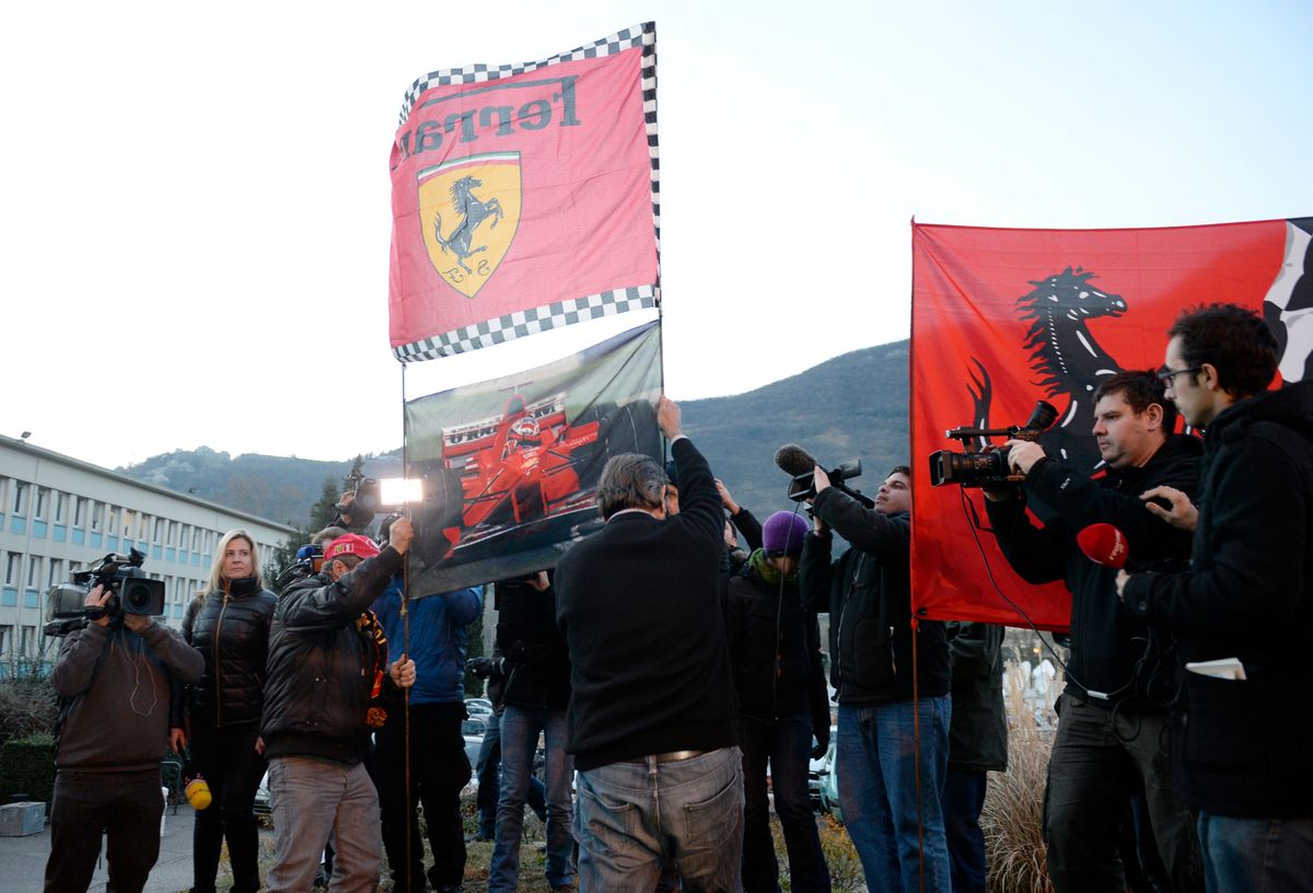 Los aficionados exhiben banderas de Ferrari mientras se reúnen frente al Centro Hospitalario de la Universidad de Grenoble, en los Alpes franceses, donde el siete veces campeón mundial de Fórmula Uno alemán Michael Schumacher se encontraba en estado crítico después de un accidente de esquí fuera de pista. 
