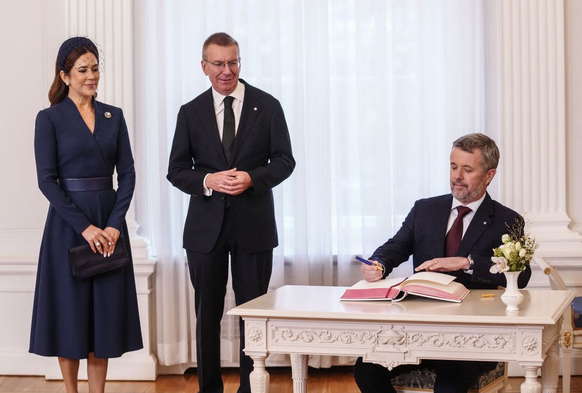Denmark's Queen Mary and Latvia's President Edgars Rinkevics (C) watch as King Frederik signs the guest book in Riga on October 28, 2025 during the two-day state visit of the Danish royal couple to Latvia. (Photo by Gints Ivuskans / AFP) (Photo by GINTS IVUSKANS/AFP via Getty Images)