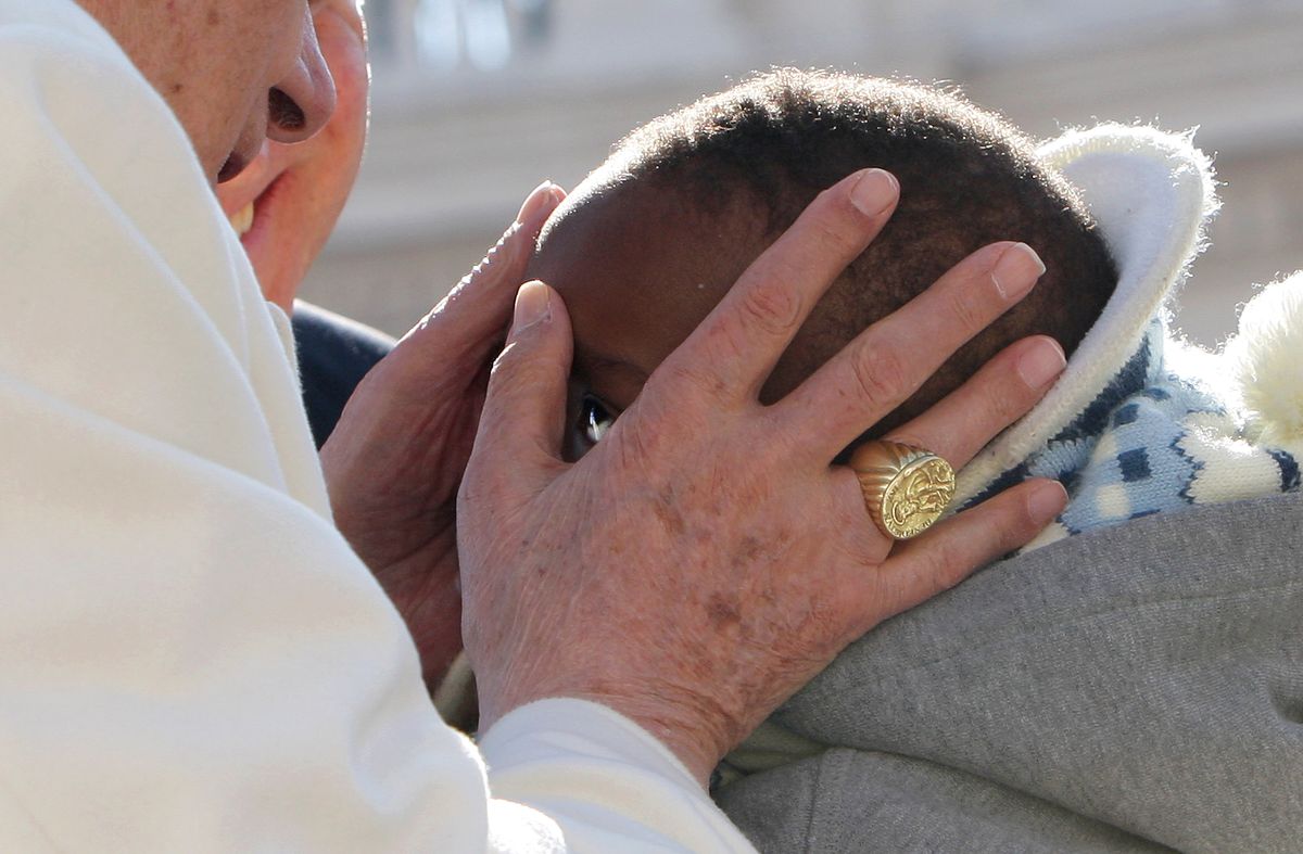 Pope Benedict XVI kisses a child as he arrives in St Peter's Square for his final general audience on February 27, 2013 in Vatican City